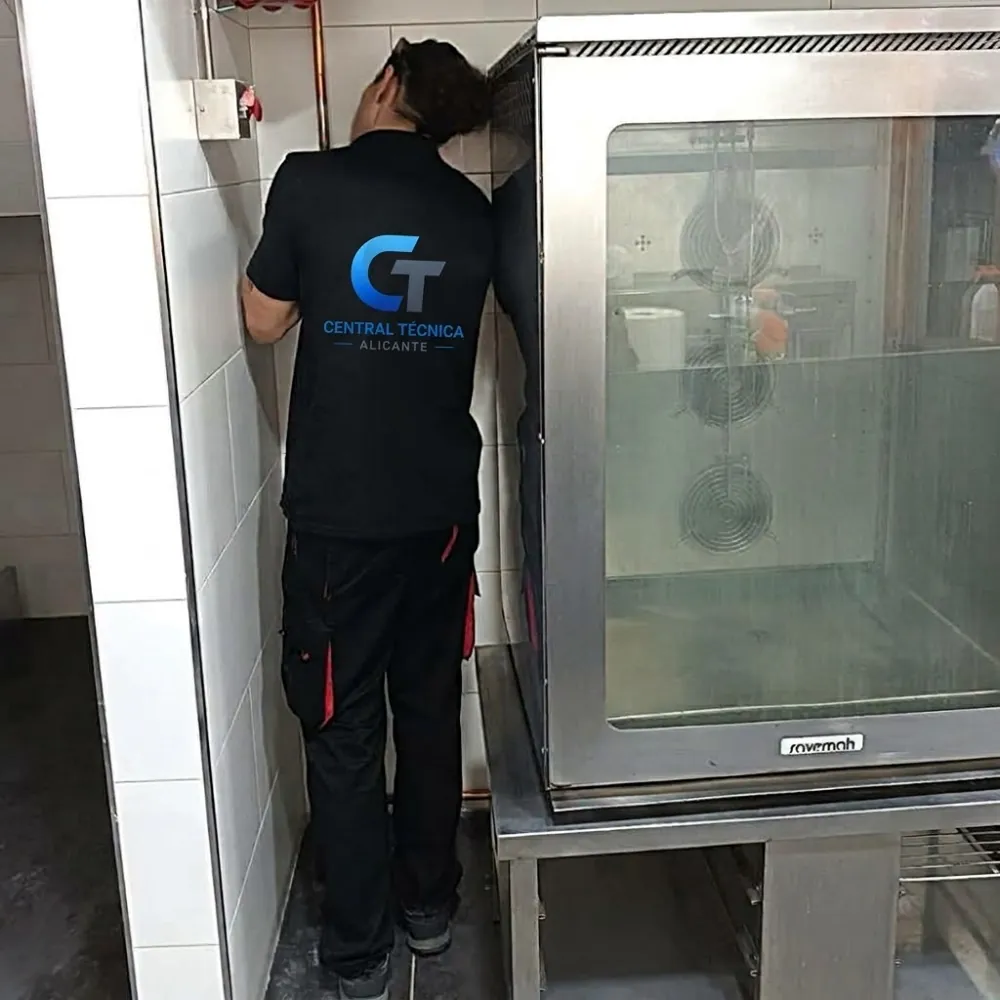 Técnico de Central Técnica Alicante sustituyendo el interruptor de puerta de un horno industrial en una cocina de Elda